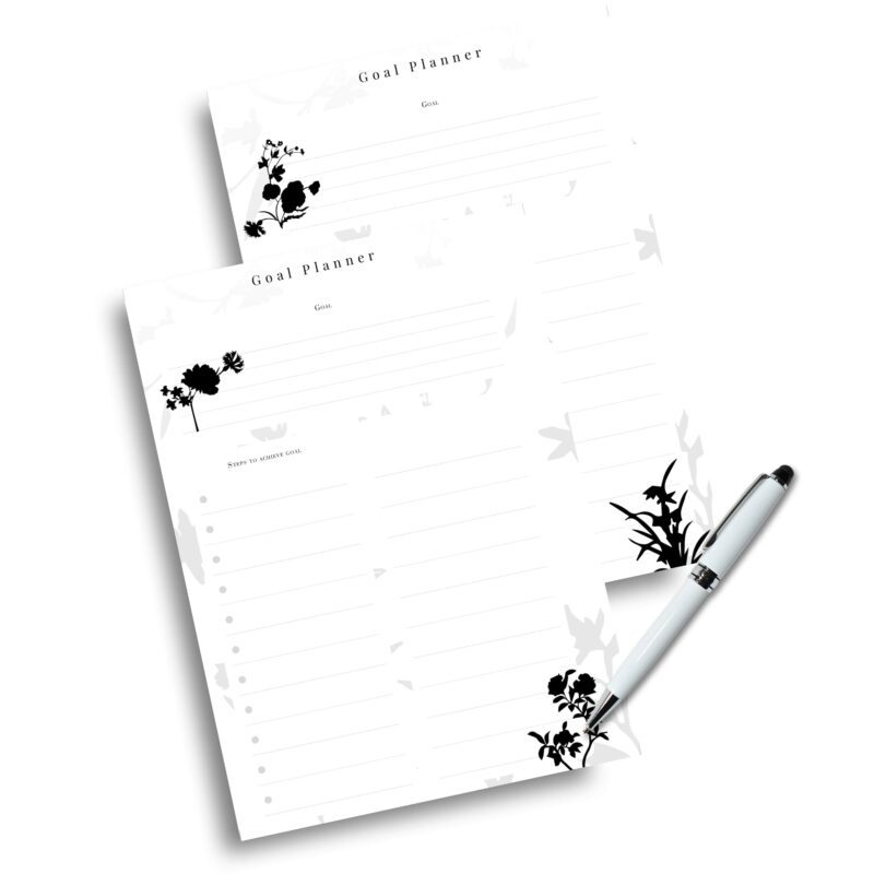 Flat lay of printed goal planner next to pen and journal